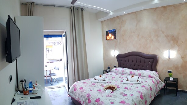 A hotel room with a bed, a desk, a television, and a view of the outside. - B&B Nazionale (Naples)