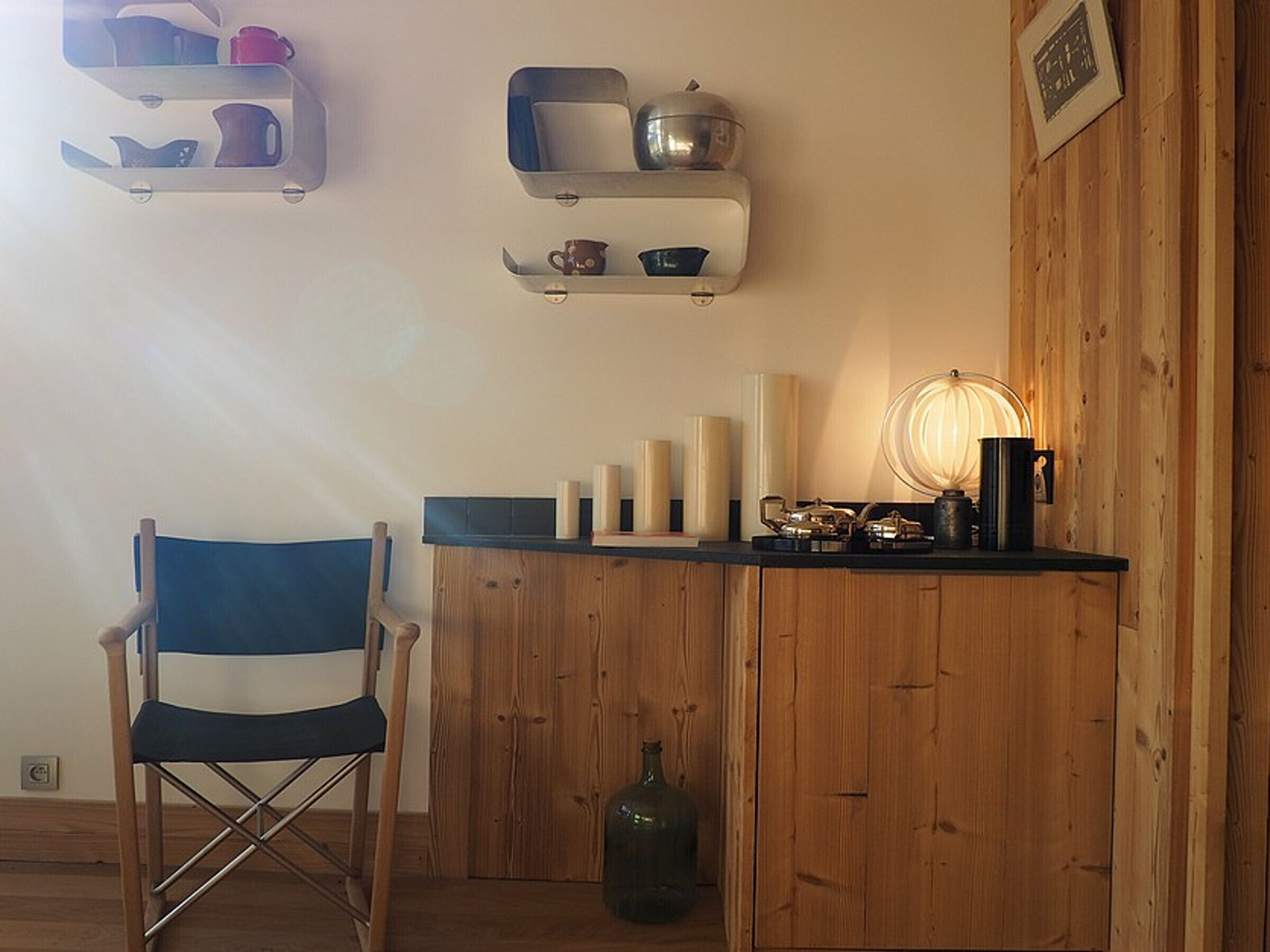 A room with a wooden cabinet, a chair, and shelves with various items.