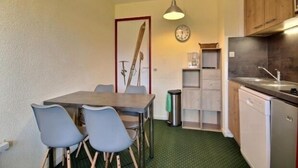 Eine kompakte Küche mit Essbereich, ausgestattet mit einer Uhr, einem Spülbecken und einem Geschirrspüler.