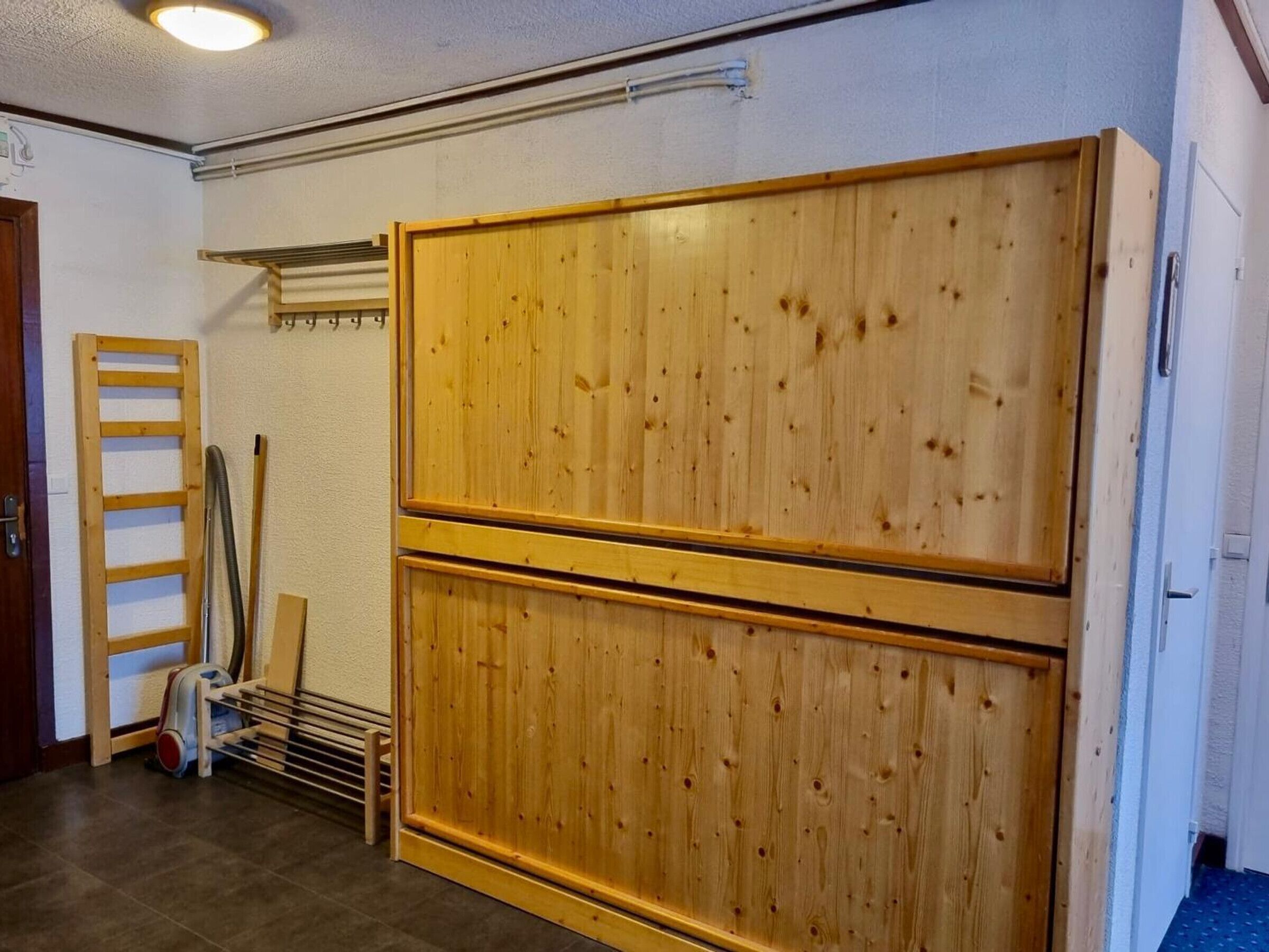 Ein Zimmer mit einem großen Holzschrank, einem Metallgestell und einer Holzleiter.