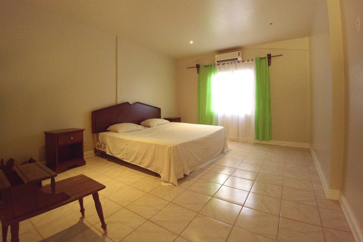 A bedroom with a bed, bedside tables, a desk, and a window with curtains.