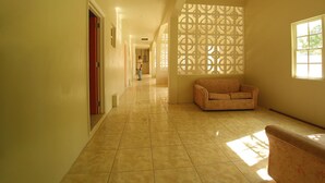 A hallway with a tiled floor, a patterned wall, and a window on the right. - Pinneys Beach Hotel Nevis (Charlestown)