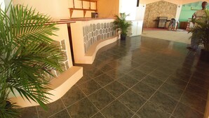 A lobby with a reception desk, a stone wall, and a tiled floor. - Pinneys Beach Hotel Nevis (Charlestown)
