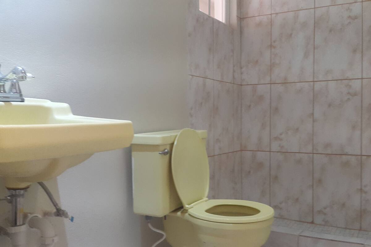 A bathroom with a toilet, sink, and tiled walls.