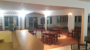 A spacious dining area with multiple tables and chairs, a large fan, and a decorative wall. - Pinneys Beach Hotel Nevis (Charlestown)