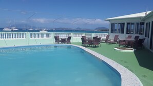 A pool area with lounge chairs and a view of the sea and boats. - Pinneys Beach Hotel Nevis (Charlestown)