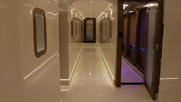 Un pasillo moderno de hotel con suelo pulido, iluminación empotrada y un ascensor central.