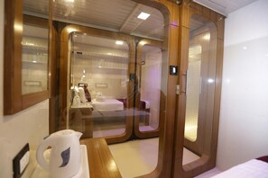 Una habitación de hotel moderna con un armario de madera, una cama y una mesita con una tetera.