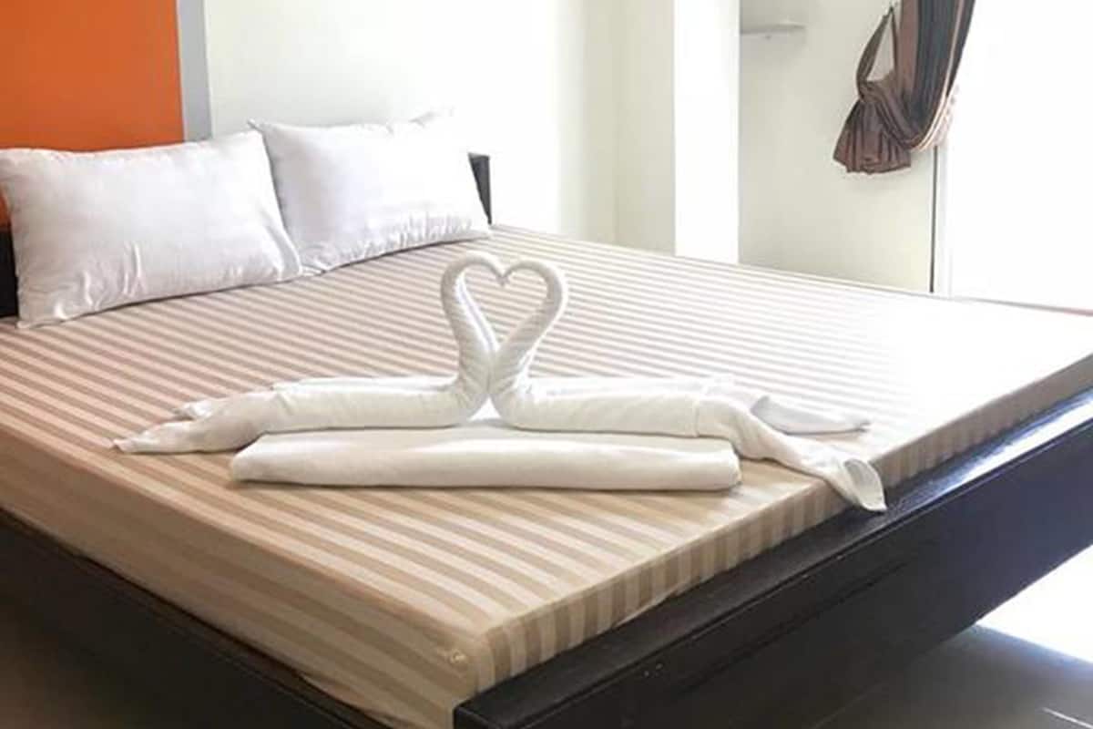 A neatly made bed with white pillows and a heart-shaped towel arrangement.