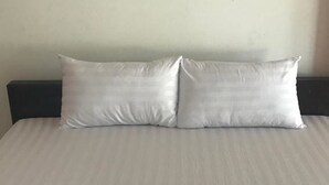 A bed with two pillows and two towels arranged in a heart shape. - Lert Sri Hotel (Suphan Buri)