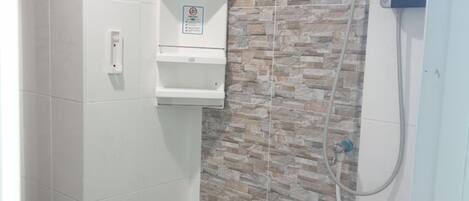 Un baño con ducha, un calentador en la pared y un secador de manos.