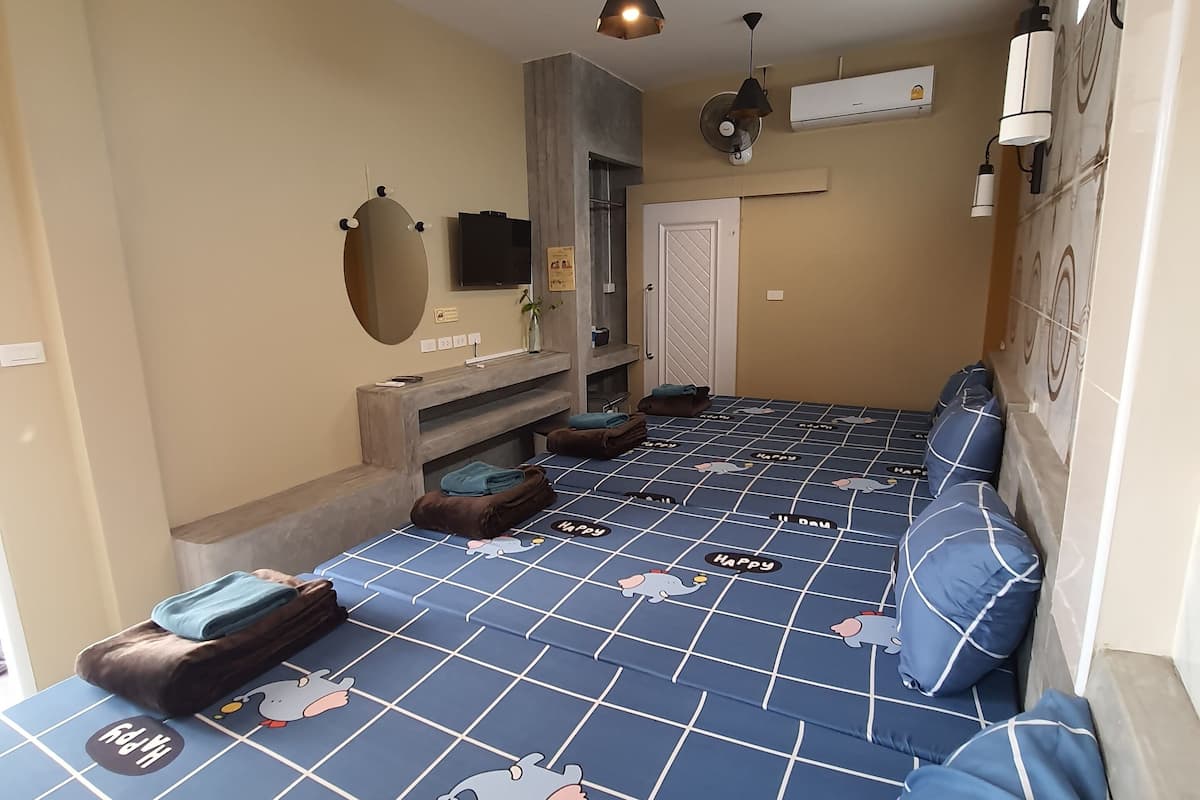 A hotel room with a large bed, a TV, a mirror, a wardrobe, and a small table.
