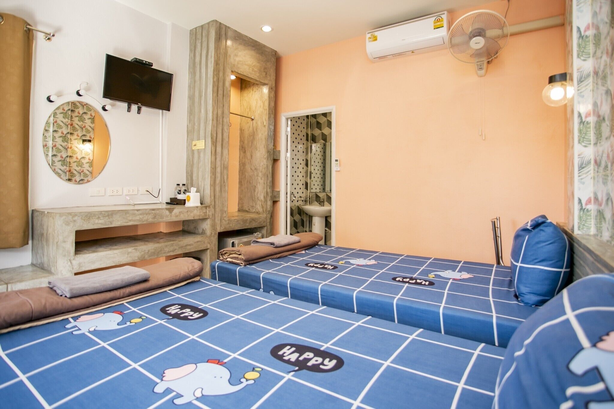 Una habitación con dos camas, televisión, espejo, lavabo y aire acondicionado.