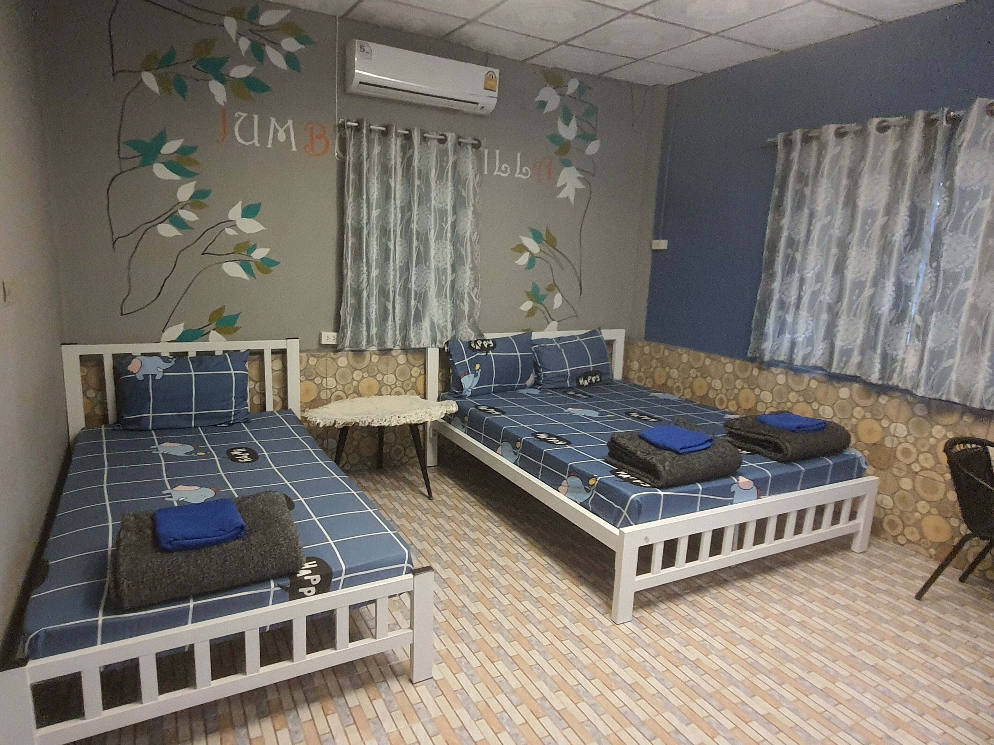Een kamer met twee éénpersoonsbedden, een tafeltje en een stoel.