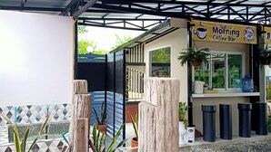 A covered outdoor area with a wooden structure, potted plants, and a sign for 'Morning Coffee Bar'. - Jumbo Villa Homestay and Resort (Wiset Chai Chan)