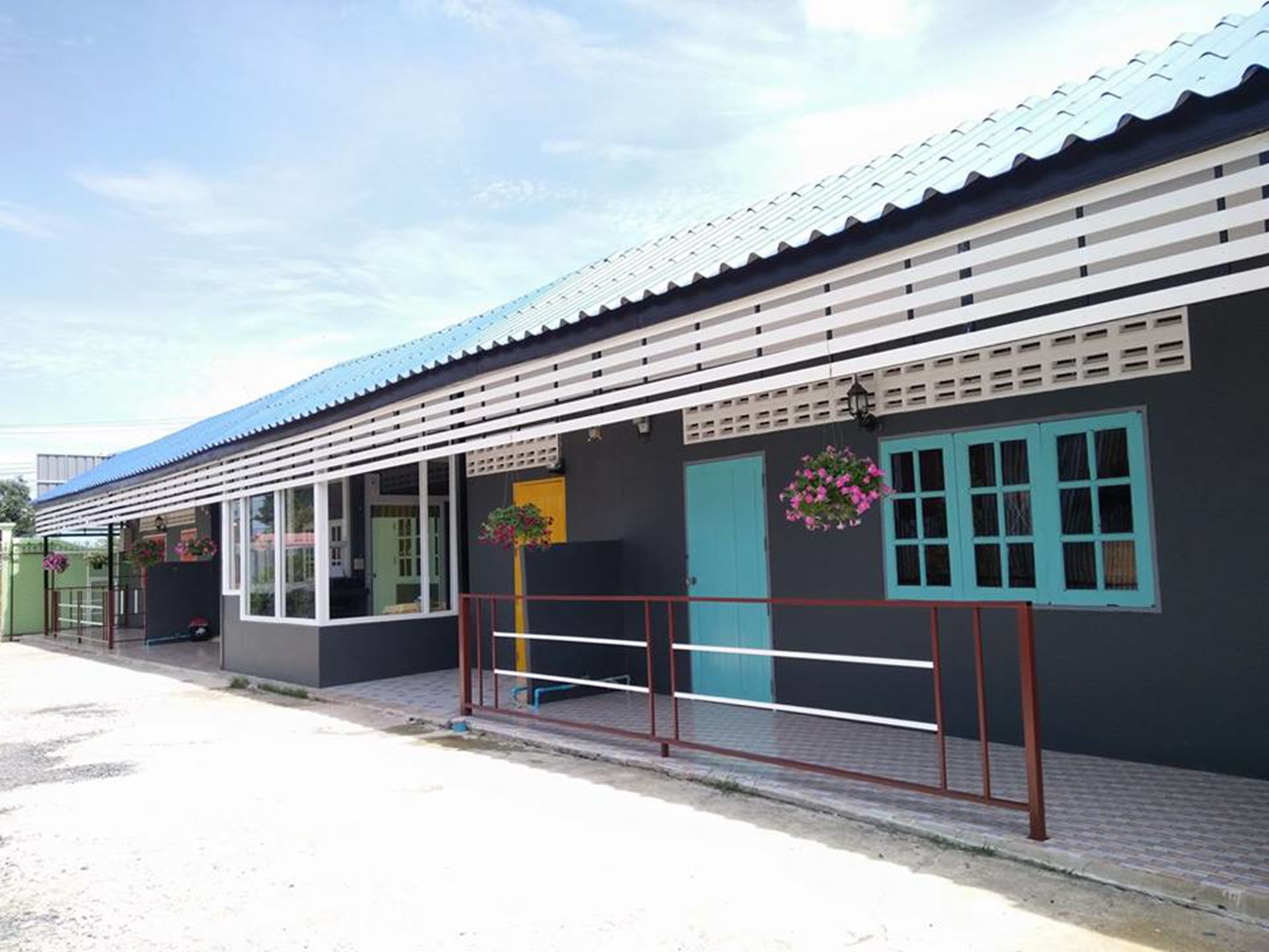 A building with a corrugated metal roof, a balcony with a metal railing, and a door with a blue window.