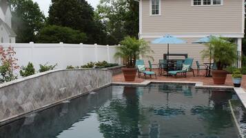 En sÀsongsöppen utomhuspool, parasoller och solstolar