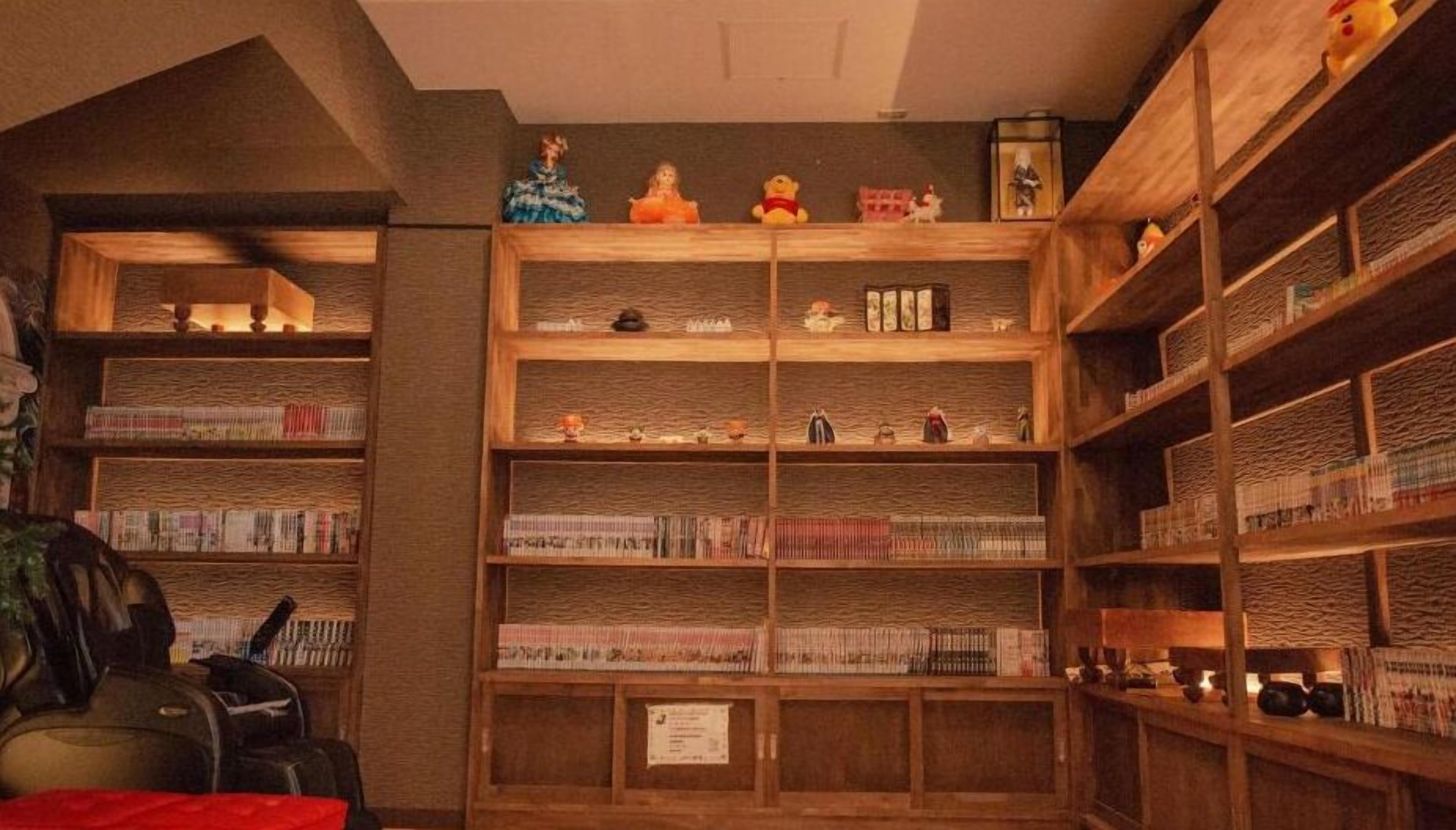A library with wooden bookshelves filled with books and various decorative items.