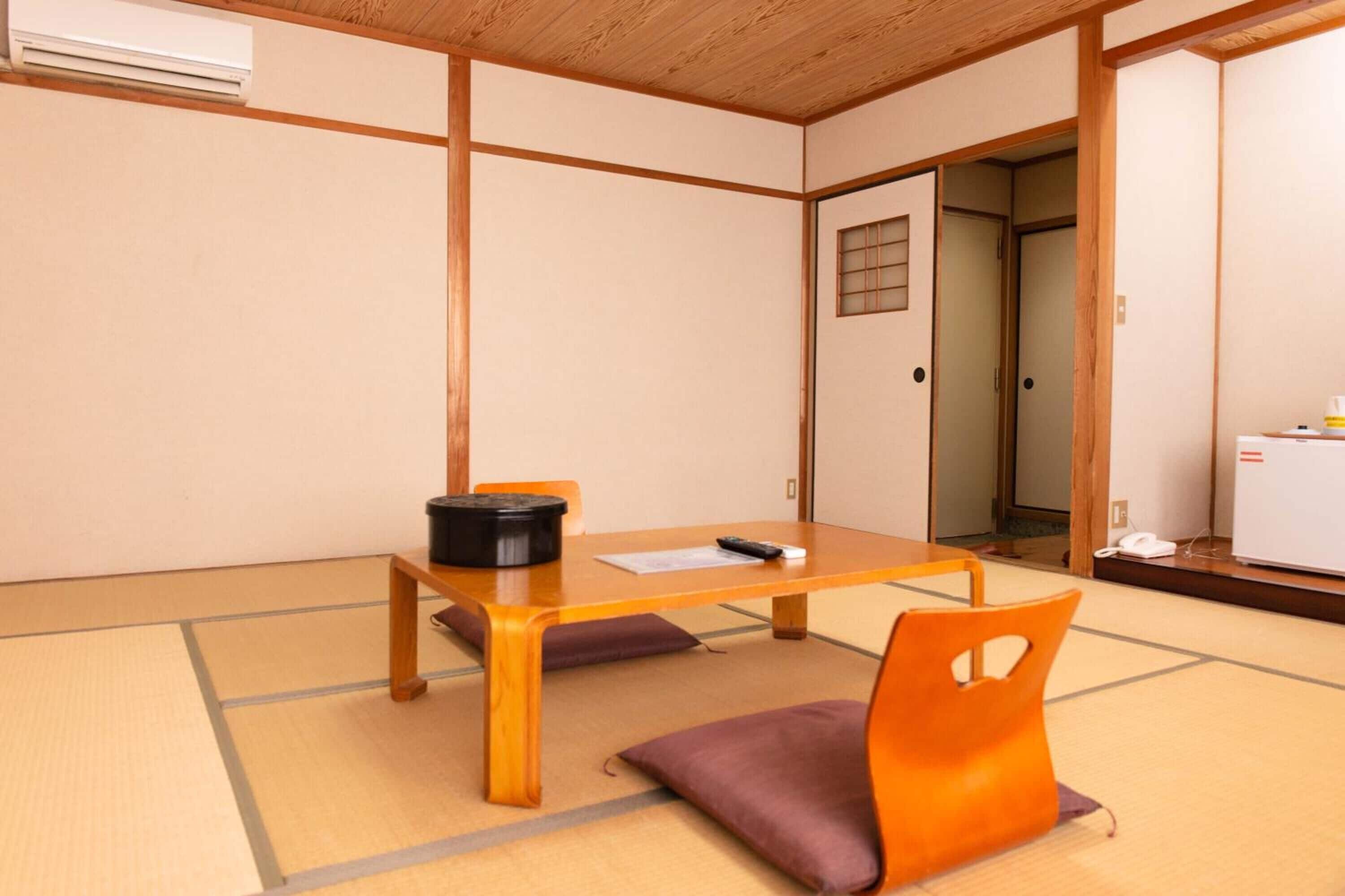 A traditional Japanese room with tatami flooring, a low wooden table, and a sliding door.