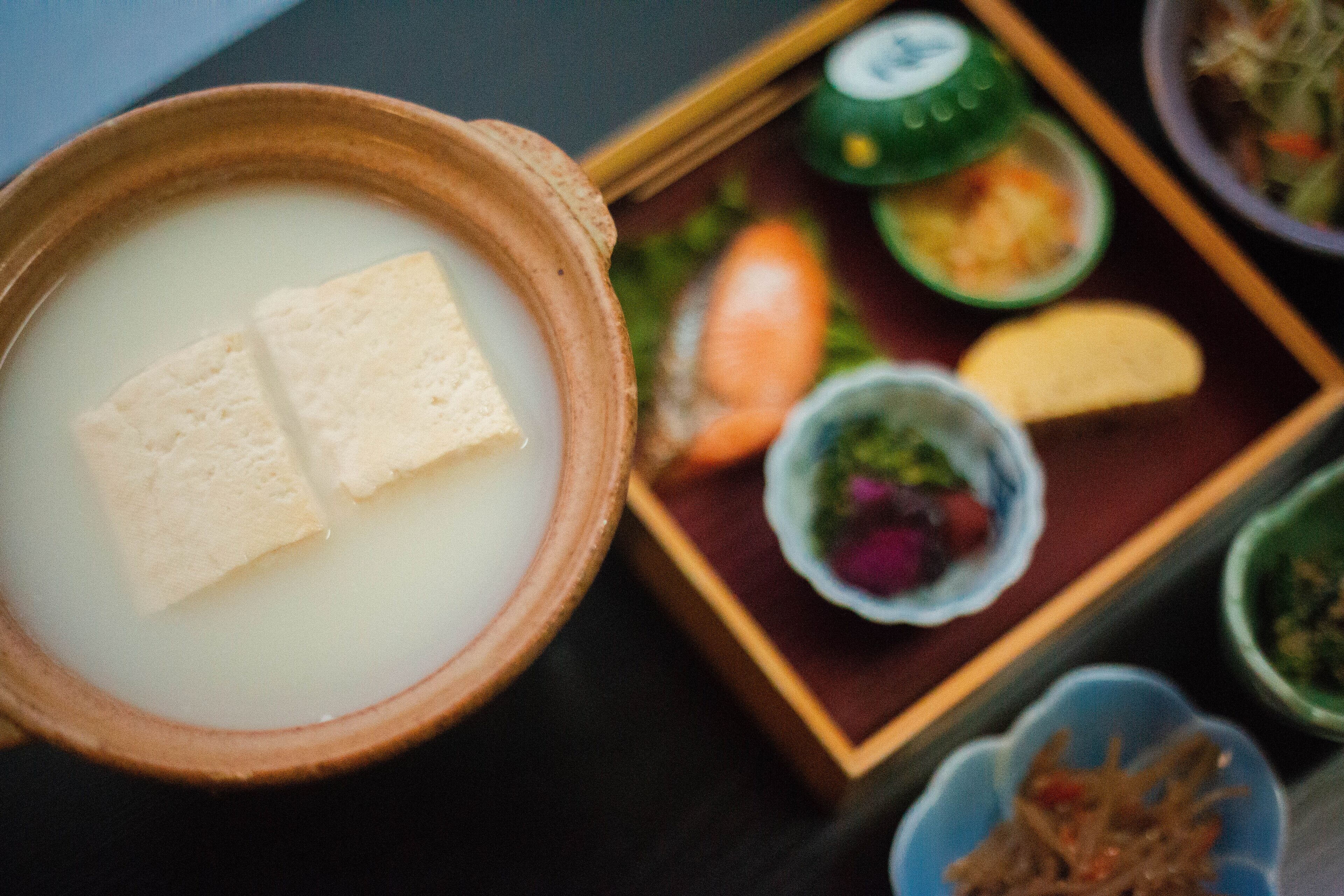 A traditional Japanese meal with a bowl of soup, tofu, and various side dishes.
