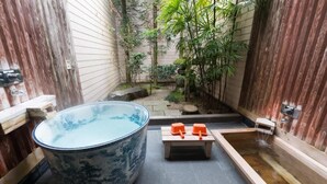 Et traditionelt japansk badeværelse med et stort, keramisk badekar, et mindre træbadekar og en sten-vask.