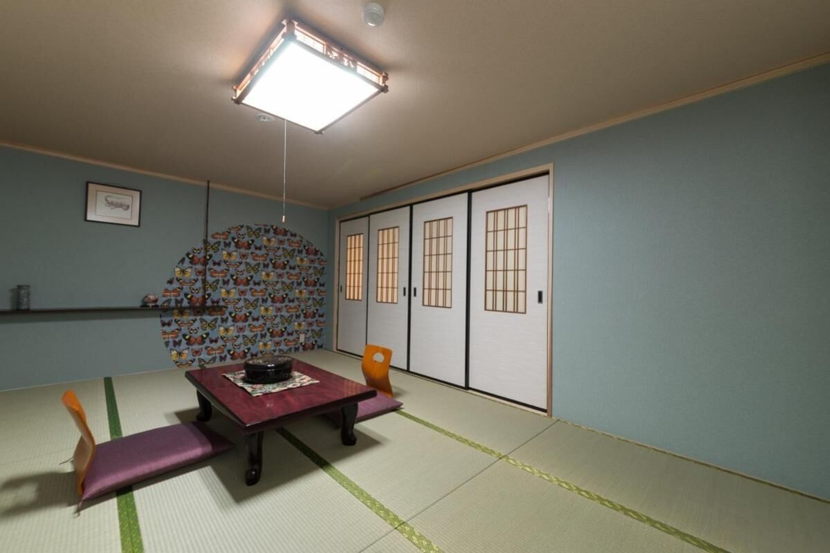 A tatami mat room with a low table, a cushion, and a wall with sliding doors.