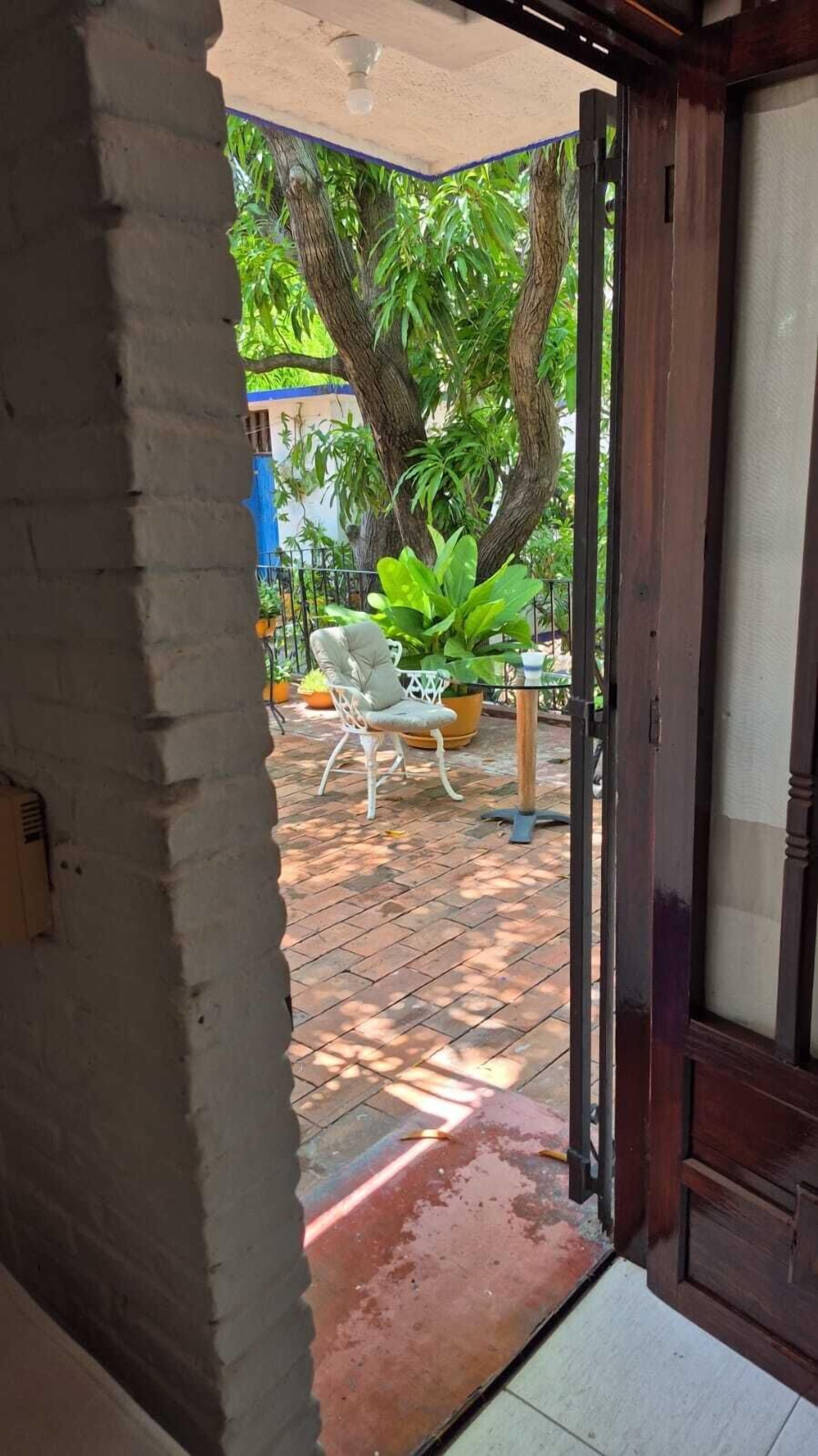 An open door leading to a patio area with a white chair, a table, and potted plants.