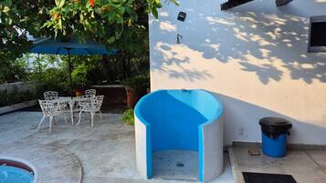 A pool with a blue interior, white outdoor furniture, and a blue trash bin.