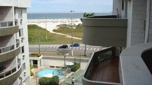 En utsikt från en balkong med utsikt över en swimmingpool, en strand och en väg med bilar.