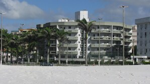 Ett hotell vid stranden med flera balkonger, palmer och en sandstrand.
