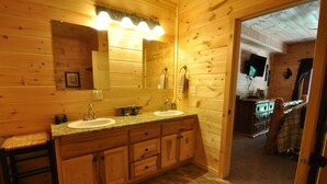 Une salle de bain rustique, avec des murs en bois, équipée de deux lavabos, d’un meuble-lavabo et d’un miroir.