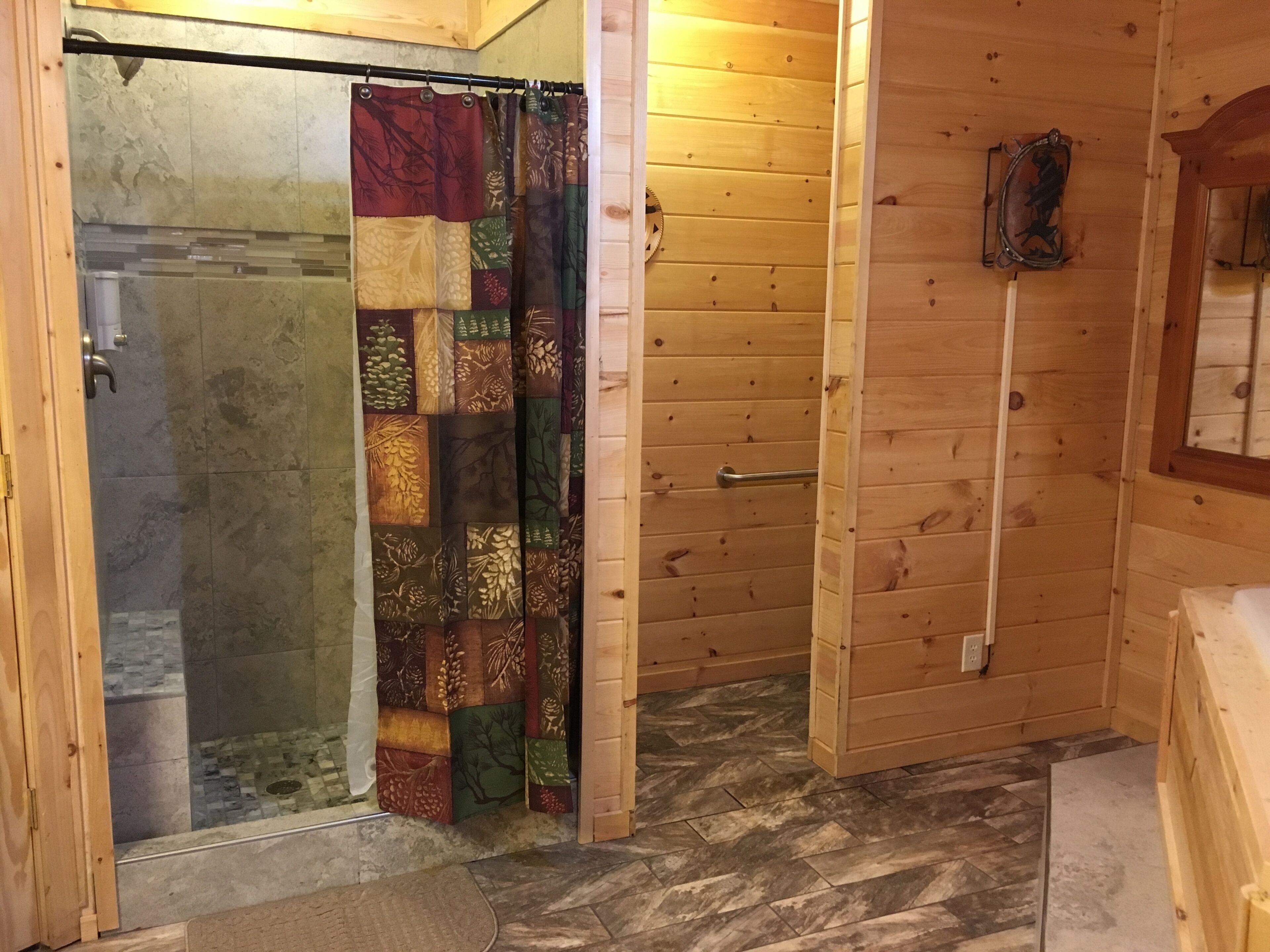 Un baño con ducha, pared de madera y suelo de baldosas.