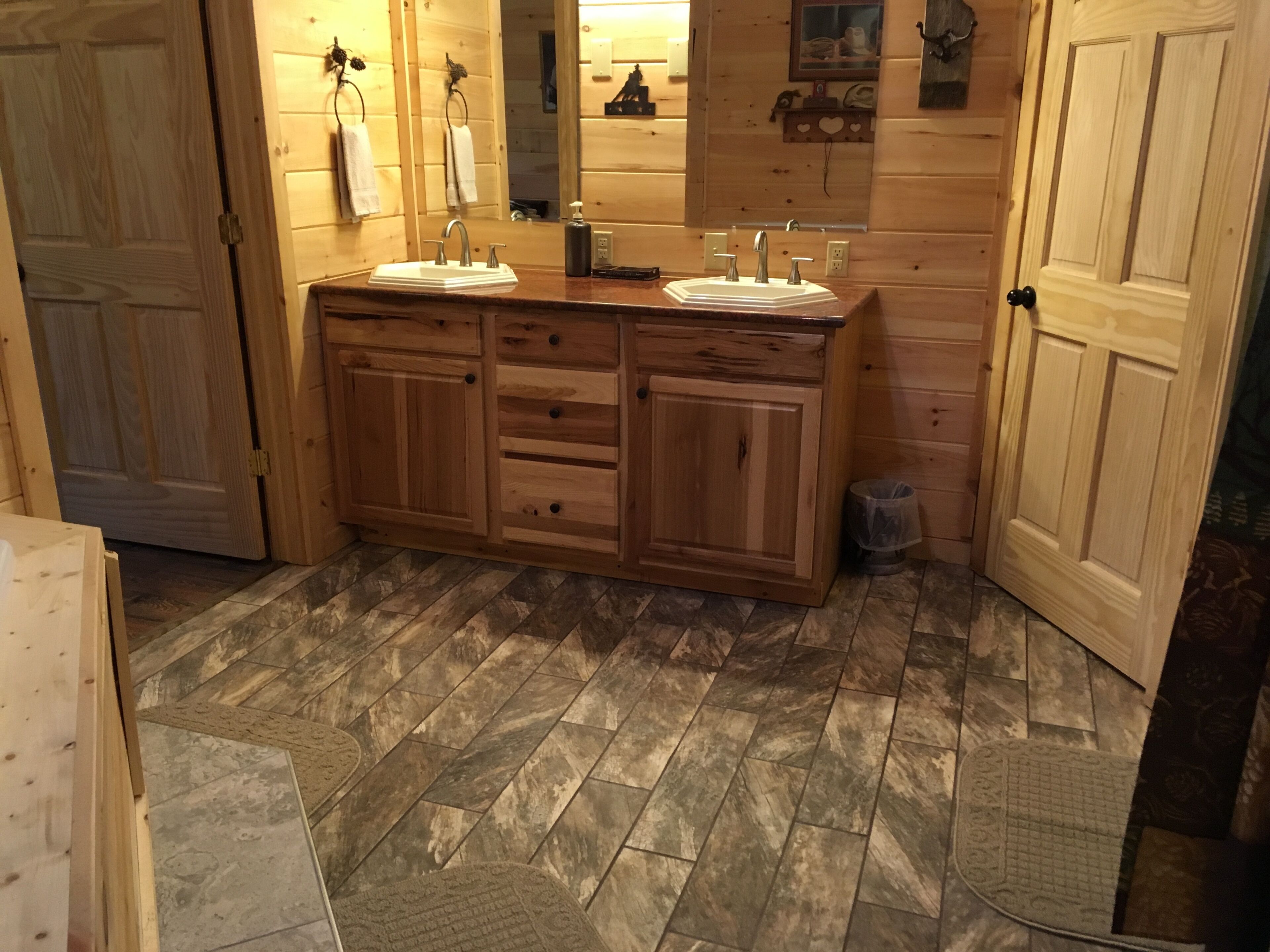 A wooden cabin-style bathroom with two sinks, a mirror, and a wooden vanity.