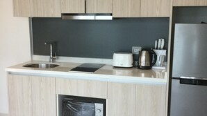A modern kitchen with wooden cabinets, a stainless steel refrigerator, a built-in oven, and a coffee maker. - Brand new resort close to beach at Pratumnak Hill (Pattaya City)