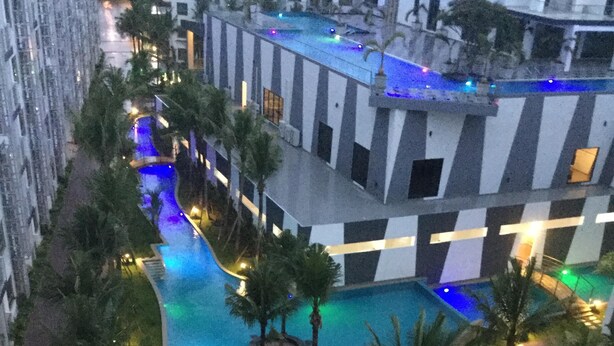 An aerial view of a hotel with a swimming pool, palm trees, and a checkered building facade. - Brand new resort close to beach at Pratumnak Hill (Pattaya City)