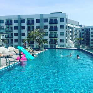 Een buitenzwembad, een zwembad op het dak en ligstoelen