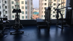 A gym with exercise equipment, a large window, and a view of high-rise buildings. - Brand new resort close to beach at Pratumnak Hill (Pattaya City)