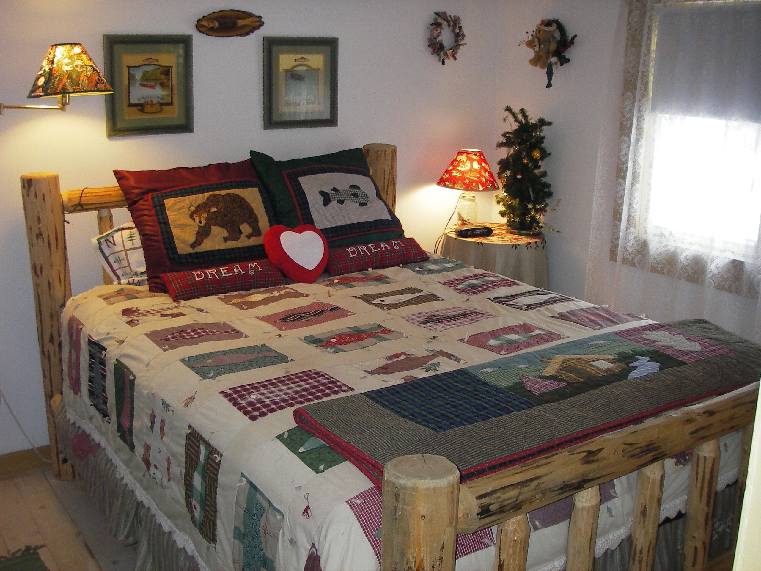 A cozy bedroom with a wooden bed frame, a quilted bedspread, and a small bedside table with a lamp.