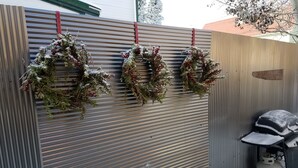 Trois couronnes sont suspendues à un mur en métal ondulé.
