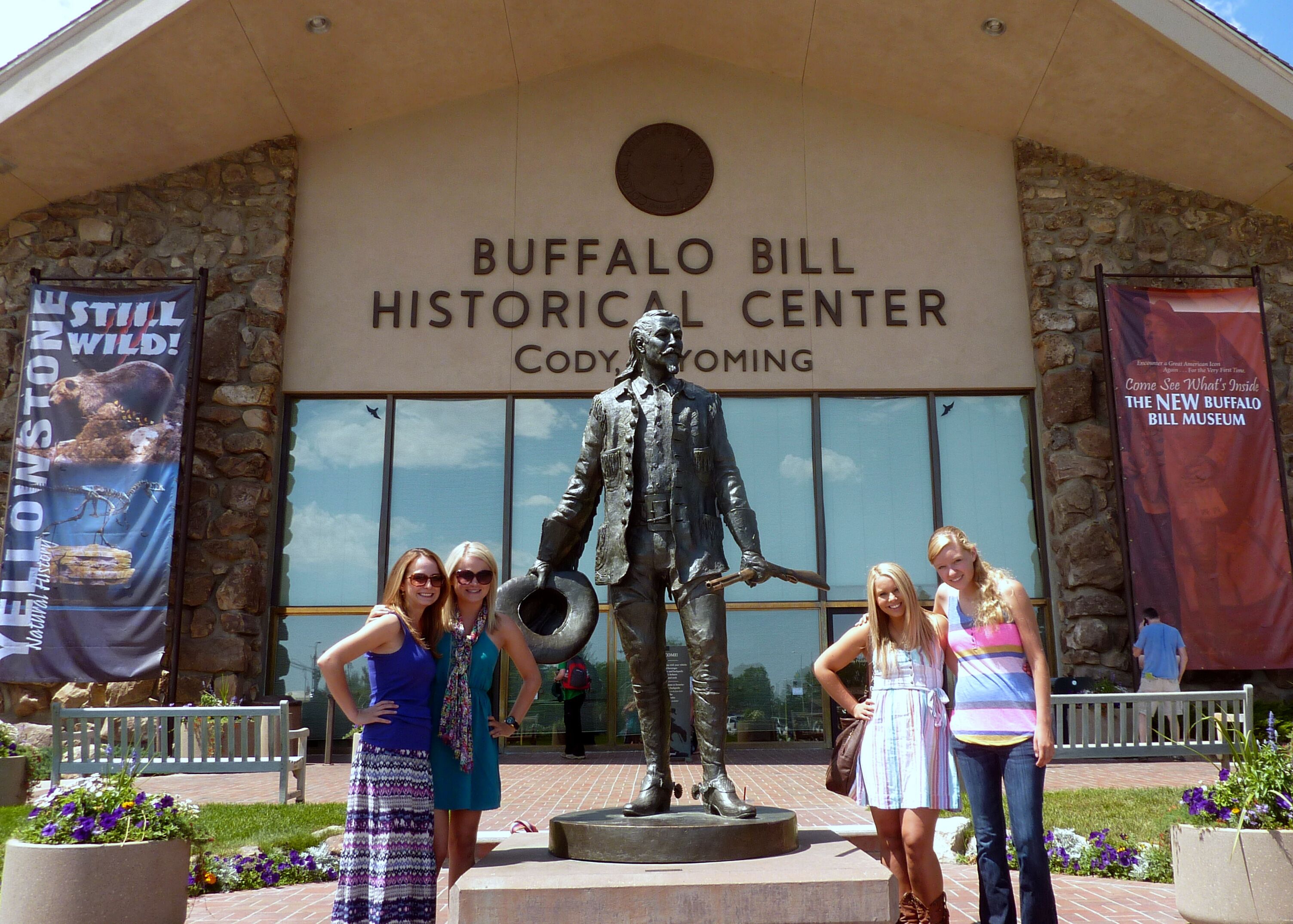 L'ingresso del Buffalo Bill Historical Center con una statua di Cody, un muro in pietra e delle bandiere.