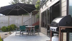 An outdoor patio with a grill, chairs, and a large umbrella.