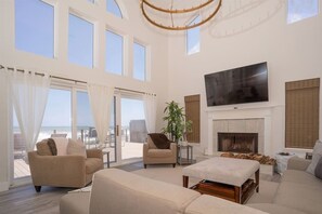 Relax in this spacious living room with a high ceiling and stunning beach views.