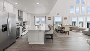 A spacious kitchen with a central island, a dining area with a view, and a large window overlooking the sea. - 4 BR Oceanfront | Large Deck, Handicap Friendly, Fire Pit & Putting Green! (Ponte Vedra Beach)