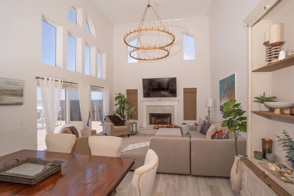 Relax in a spacious living area with a high ceiling, featuring a large L-shaped sofa, flat-screen TV, and dining table.