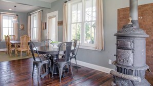 Un coin repas avec une table ronde, des chaises et un poêle à bois rustique.