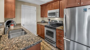 A kitchen with wooden cabinets, a stainless steel refrigerator, a microwave, an oven, and a sink. - Immaculate PC condo - Extended Stay or Monthly rental, KING BED,  carport, W/D (Park City)