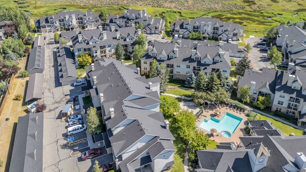 A residential area with modern houses, a swimming pool, and a hilly landscape in the background. - Immaculate PC condo - Extended Stay or Monthly rental, KING BED,  carport, W/D (Park City)