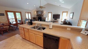 A spacious kitchen with granite countertops, a dishwasher, and a dining area with wooden chairs. - Great Dock, Wifi!  Come Visit "Captain's Choice"! (Huddleston)