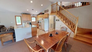 A spacious kitchen with wooden cabinets, a dining area with a wooden table and chairs, and a wooden staircase. - Great Dock, Wifi!  Come Visit "Captain's Choice"! (Huddleston)