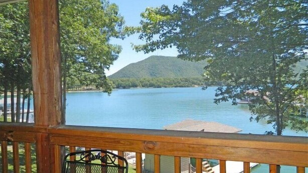 A wooden deck with a metal chair, overlooking a lake with a mountain in the background. - Great Dock, Wifi!  Come Visit "Captain's Choice"! (Huddleston)